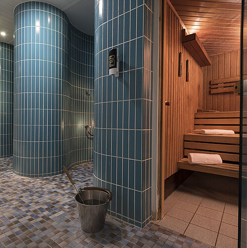 Espace sauna du Maritim Hotel Berlin avec des bancs de sauna traditionnels en bois,des carreaux bleus et des douches modernes