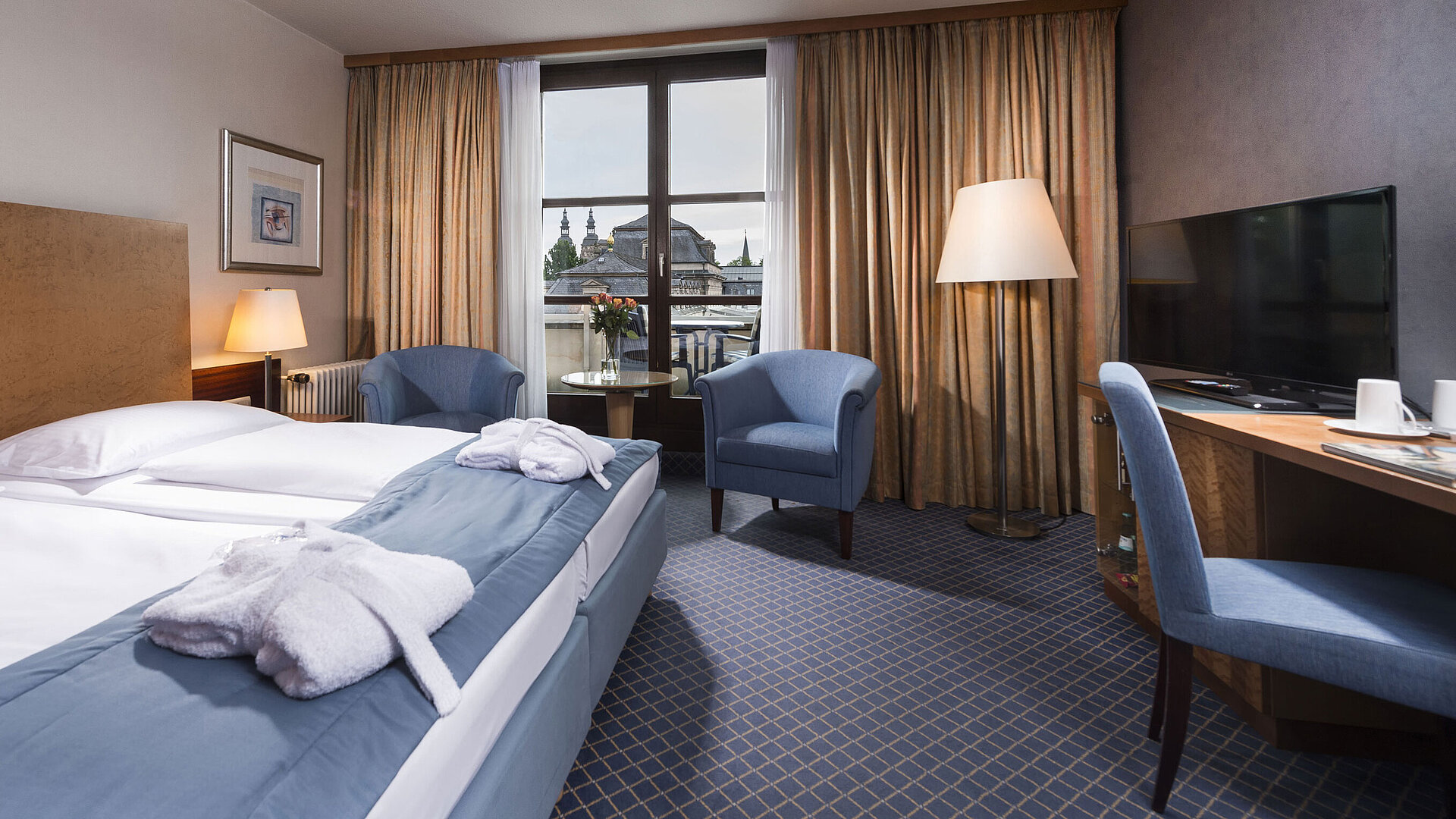 Elegante habitación Superior en el Maritim Hotel Fulda con cama doble, zona de estar y balcón con vistas a la ciudad.