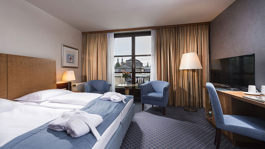 Elegante habitación Superior en el Maritim Hotel Fulda con cama doble, zona de estar y balcón con vistas a la ciudad.