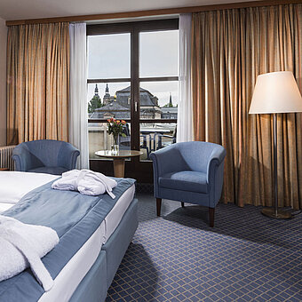 Elegante habitación Superior en el Maritim Hotel Fulda con cama doble, zona de estar y balcón con vistas a la ciudad.