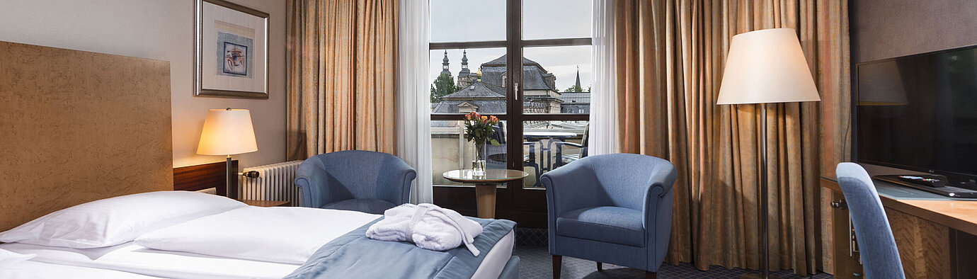 Chambre supérieure élégante au Maritim Hotel Fulda avec lit double, coin salon et balcon avec vue sur la ville.
