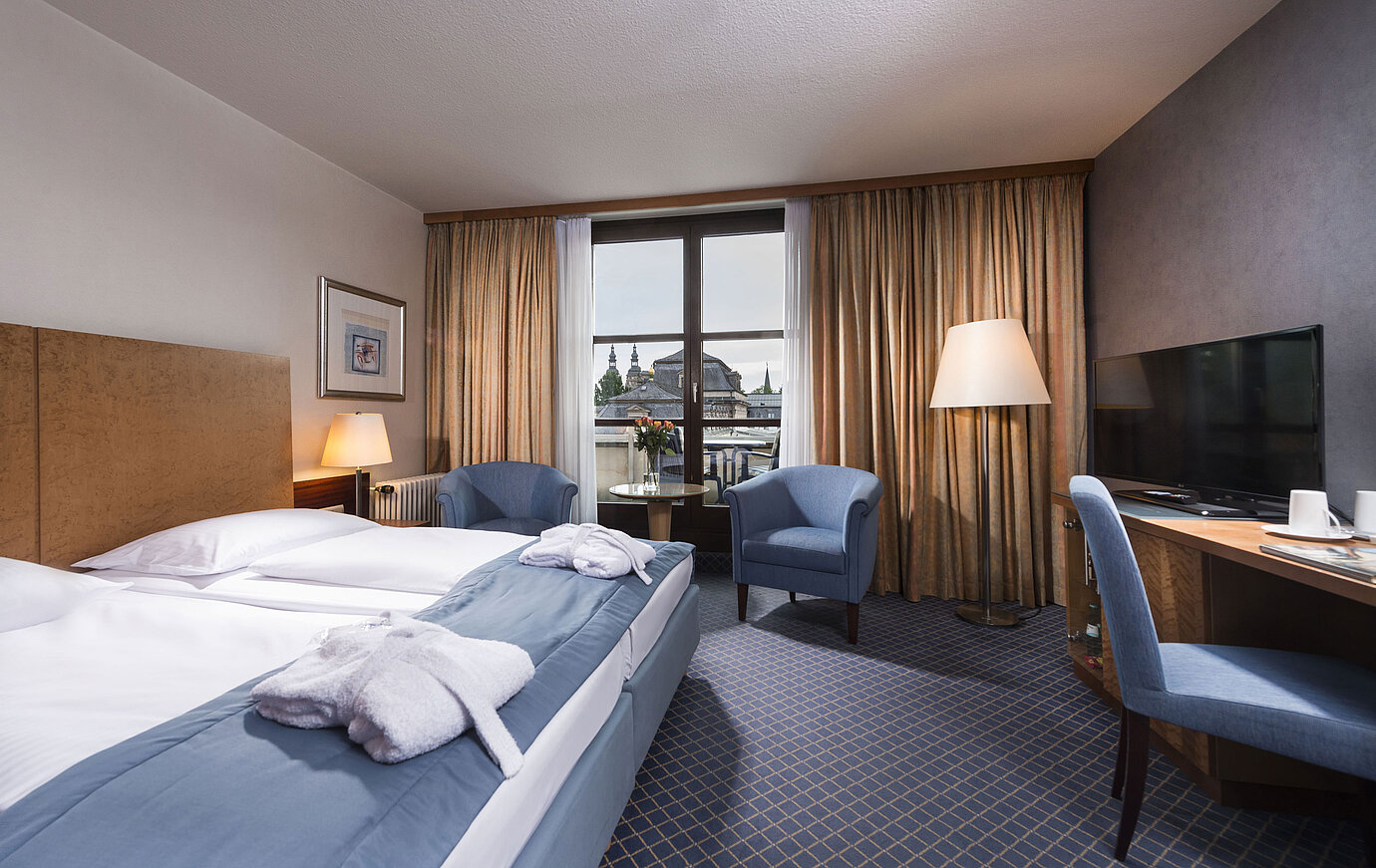 Elegante habitación Superior en el Maritim Hotel Fulda con cama doble, zona de estar y balcón con vistas a la ciudad.