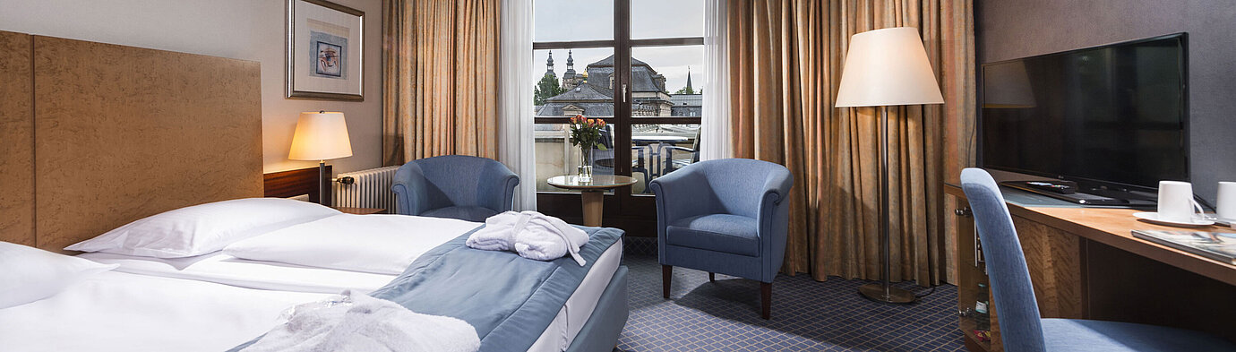 Chambre supérieure élégante au Maritim Hotel Fulda avec lit double, coin salon et balcon avec vue sur la ville.