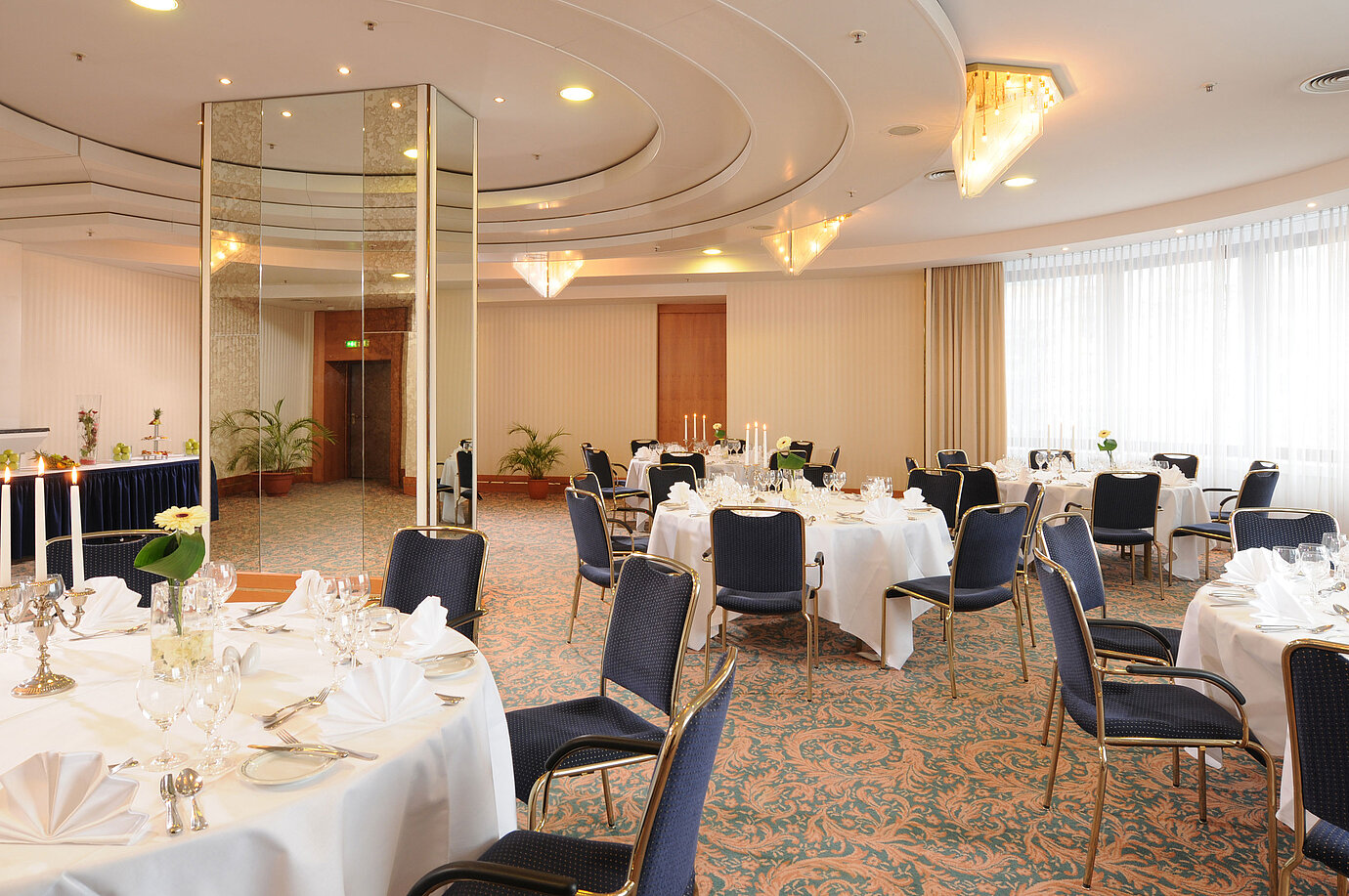 Salon Dresden en el Maritim Hotel Magdeburg con mesas blancas elegantes, candelabros y luz sofisticada para eventos festivos.