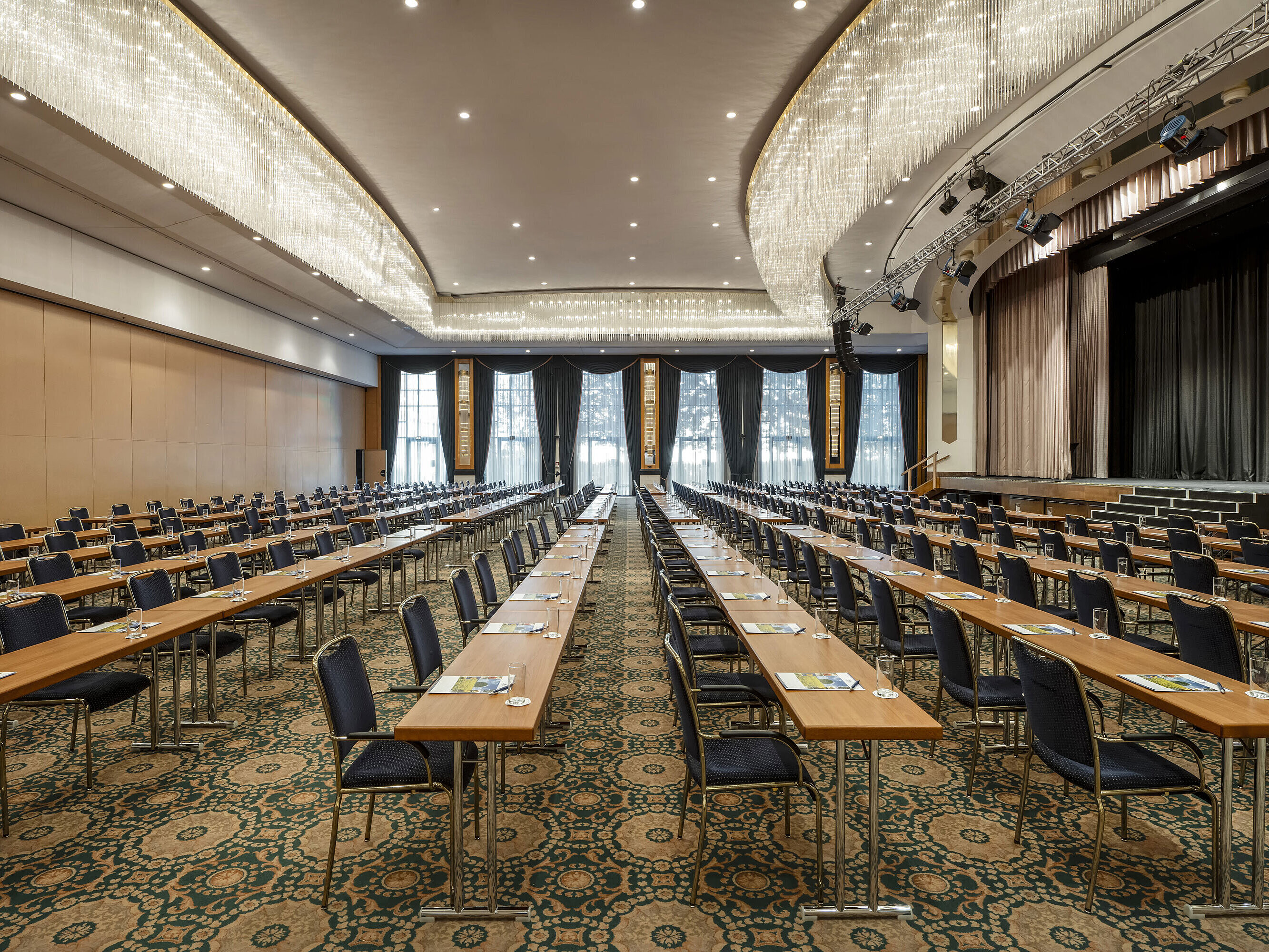 Salón magnífico en el Maritim Hotel Magdeburg con escenario, asientos en fila y lujosa lámpara de araña.