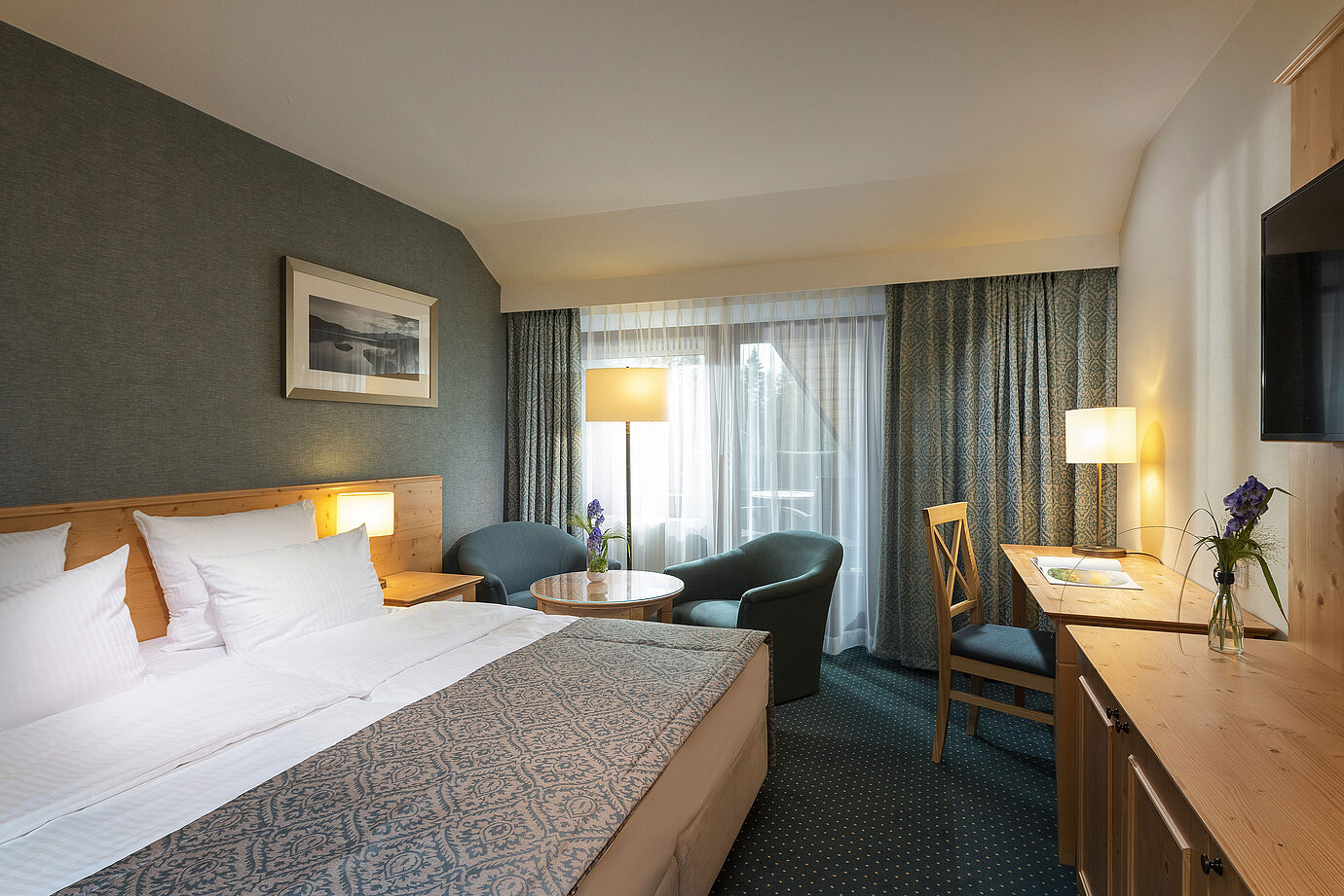 Cosy double room with desk and seating area at Maritim Hotel Titisee