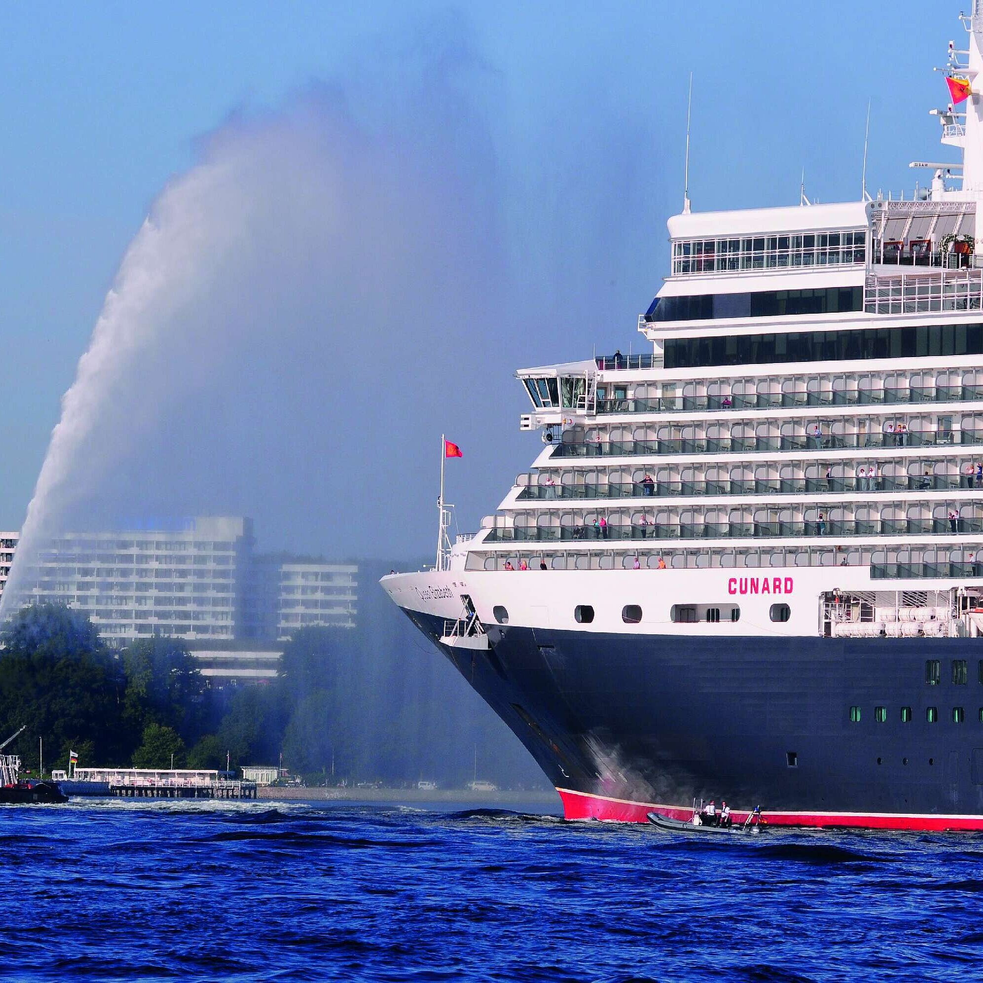 Vue extérieure du Maritim Hotel Kiel, au premier plan le bateau de croisière Queen Elizabeth et un remorqueur sur l'eau.