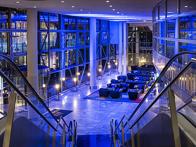 Hall du Maritim Hotel Frankfurt illuminé la nuit avec des espaces lounge élégants.