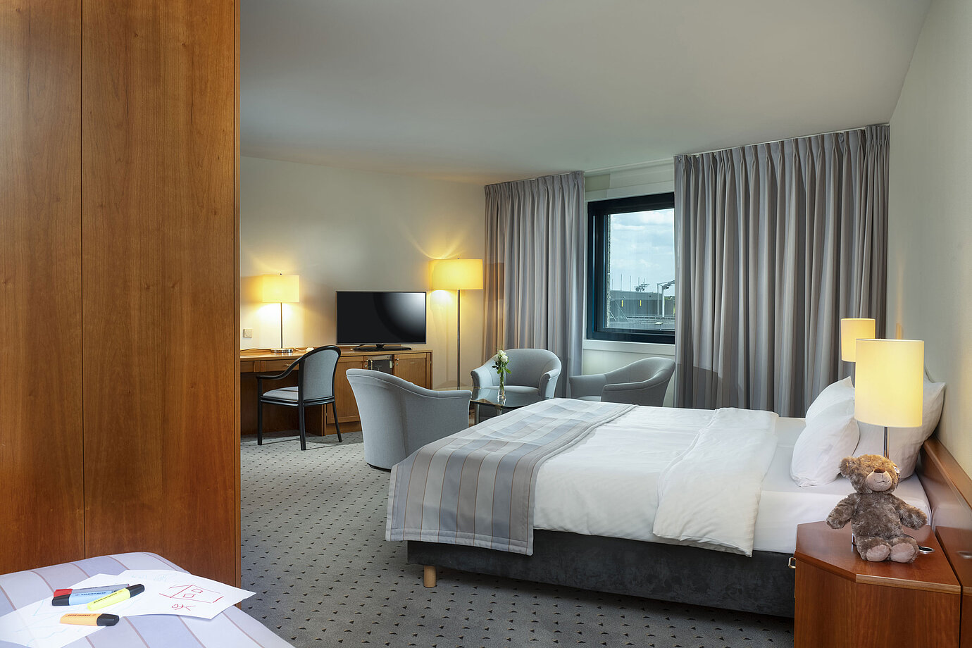 Camera familiare spaziosa con letto matrimoniale, area salotto e vista aeroporto al Maritim Hotel Hannover.