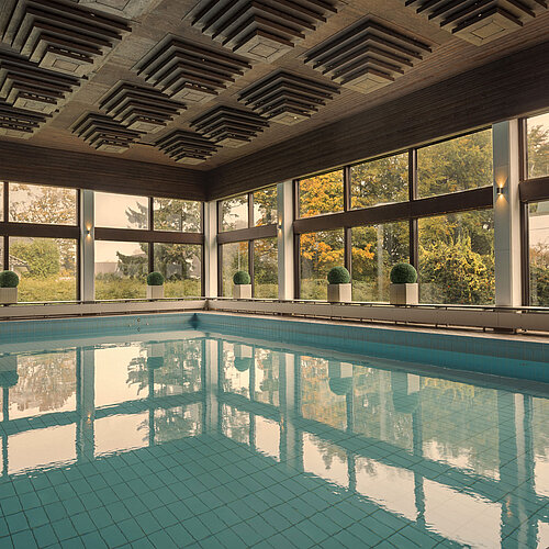 Piscine intérieure du Maritim Hotel Kiel, entourée de grandes fenêtres donnant sur la verdure.