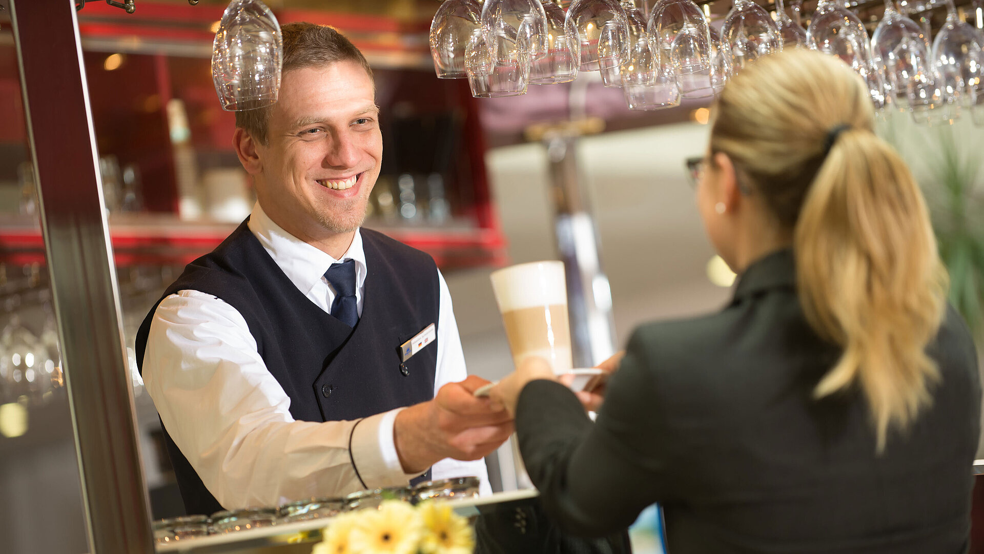 Lobby bar A bartender handing a drink to a guest at the bar in Maritim Hotel with a friendly smile
