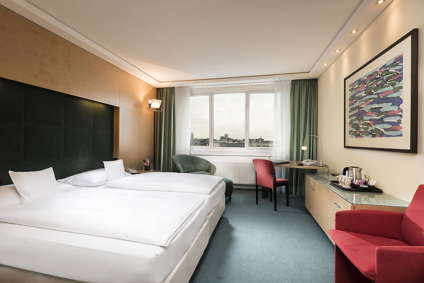 Chambre Confort à l'hôtel Maritim proArte Berlin avec lit double, bureau, fauteuil et vue sur la ville.