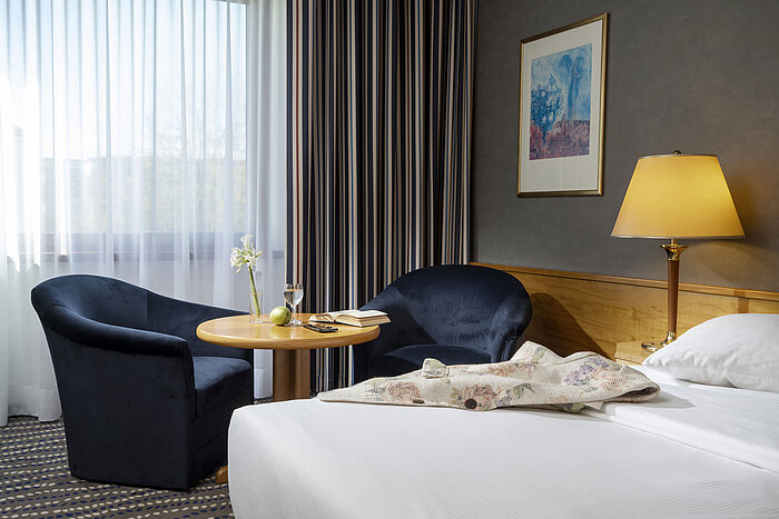 Coin salon dans la chambre d'hôtel avec table, livre, verre d'eau et pomme, parfait pour se détendre
