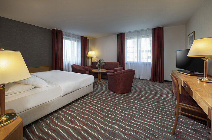 Chambre studio moderne au Maritim Hotel Magdeburg avec un coin salon confortable et un lit double pour un séjour relaxant.