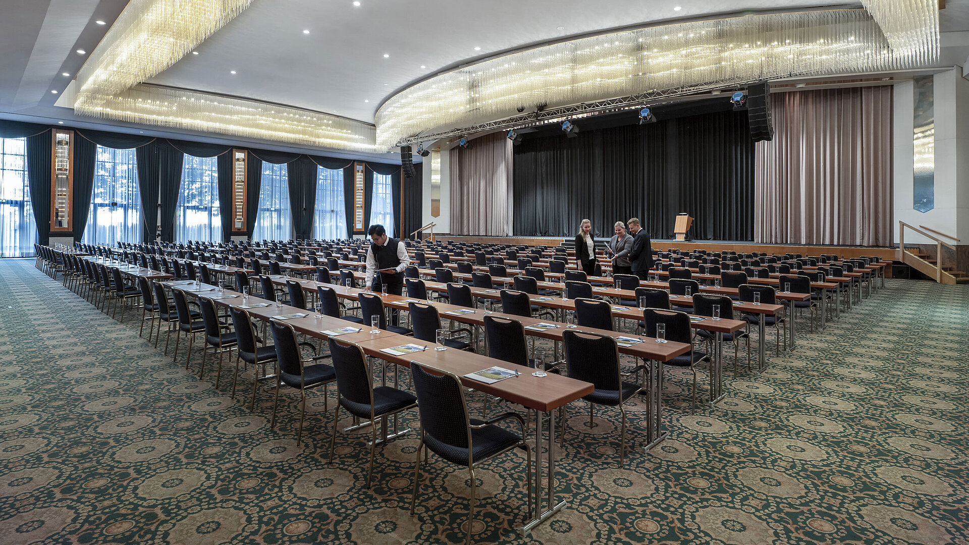Salón magnífico en el Maritim Hotel Magdeburg con escenario, asientos en fila y lujosa lámpara de araña.
