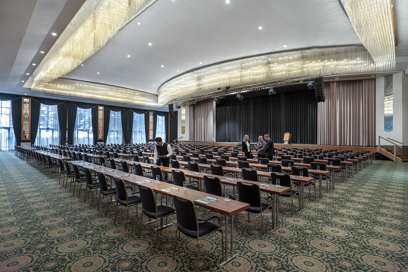 Salón magnífico en el Maritim Hotel Magdeburg con escenario, asientos en fila y lujosa lámpara de araña.