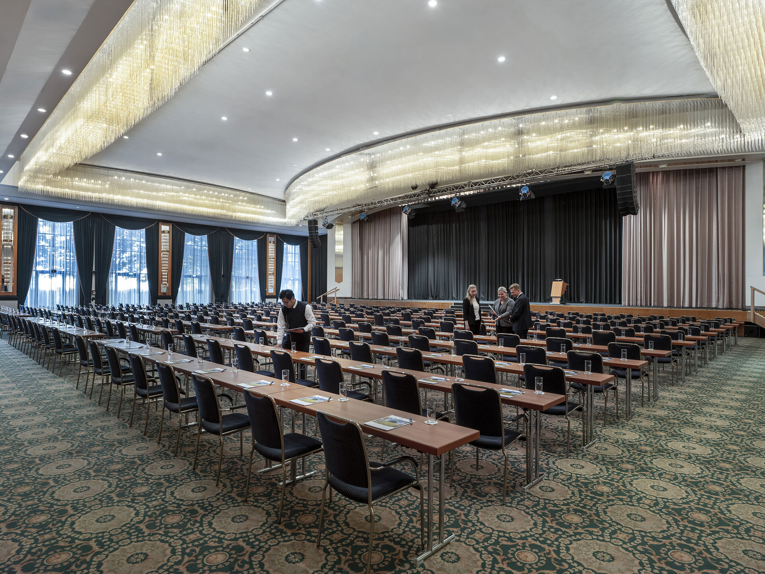 Salón magnífico en el Maritim Hotel Magdeburg con escenario, asientos en fila y lujosa lámpara de araña.