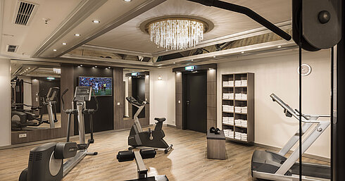 Well-equipped fitness room with cardio machines and mirrors at the Maritim Hotel Munich