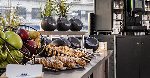 Amplia selección de café y snacks en el Maritim Hotel Magdeburg con pasteles frescos, frutas y modernas máquinas de café.