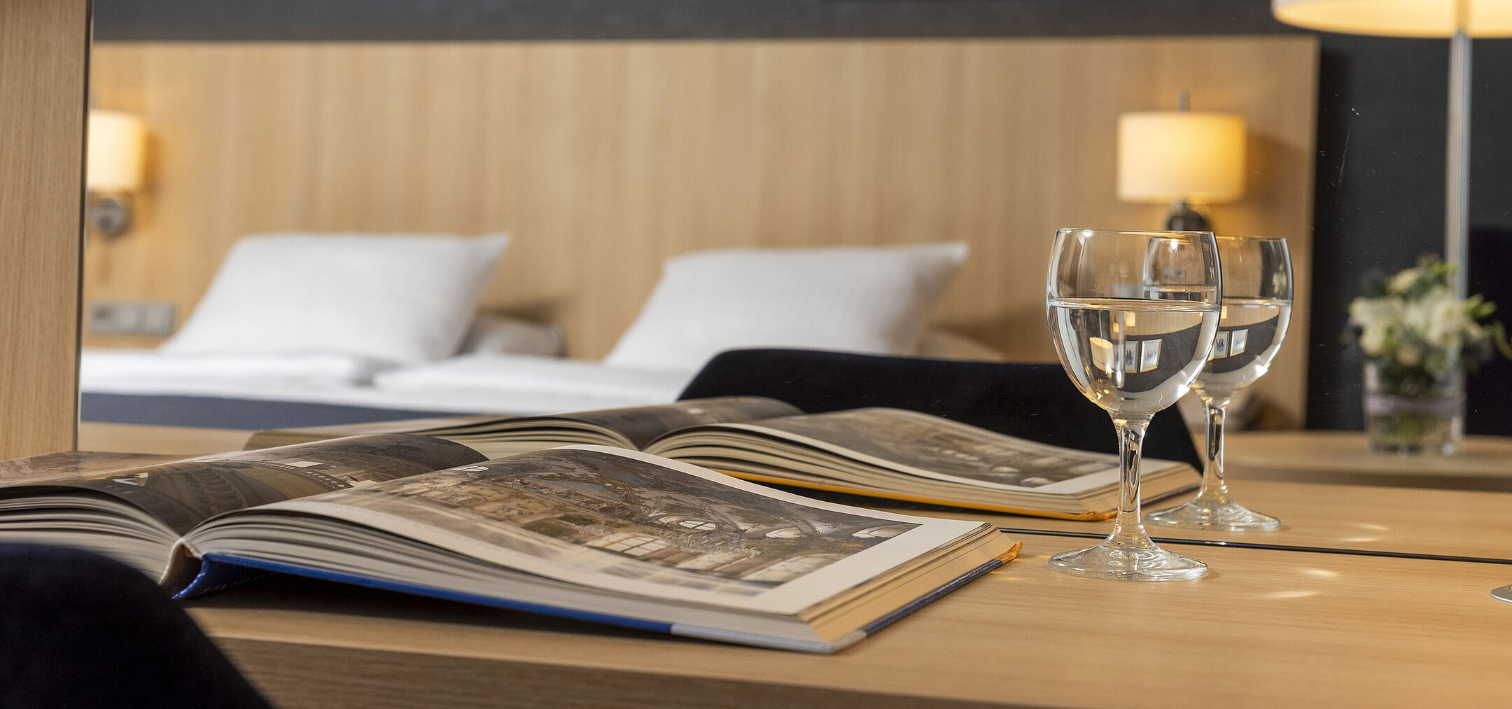 Accogliente camera Comfort al Maritim Hotel Würzburg con specchio, libro illustrato aperto e bicchieri d’acqua
