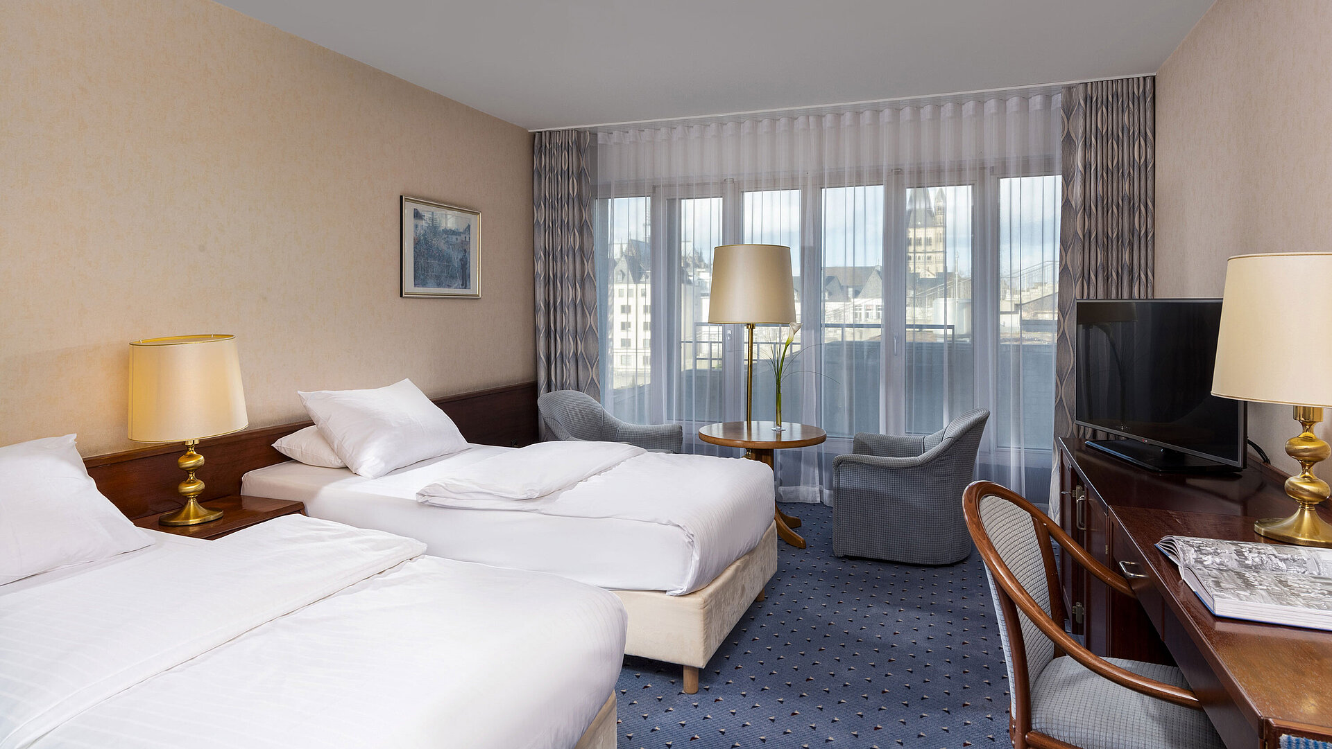 Camera Standard Twin al Maritim Hotel Colonia con due letti, area salotto, scrivania, TV a schermo piatto e ampie finestre.