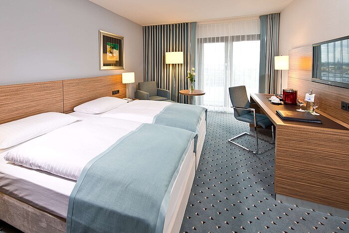 Superior room at Maritim Hotel Darmstadt with double bed, desk, seating area, and balcony view for a relaxing stay.