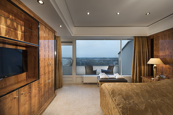 Chambre de penthouse avec meubles en bois, grande baie vitrée et vue sur le balcon au Maritim Seehotel Timmendorfer Strand.
