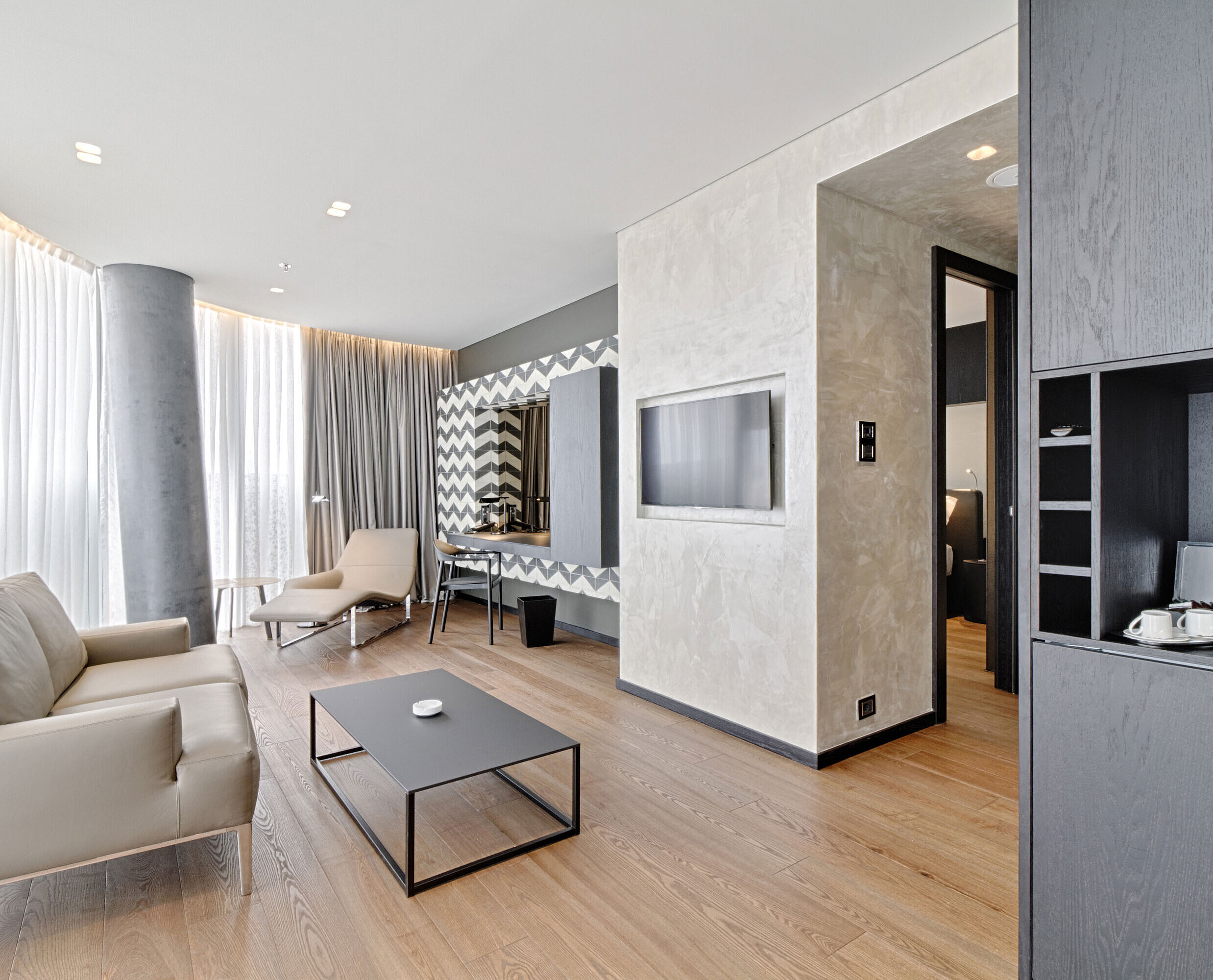 Suite Salon avec canapé, TV, miroir design et fauteuil au Maritim Hotel Plaza Tirana, baigné de lumière