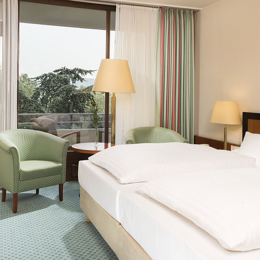 Bright hotel room at Maritim Hotel Bad Salzuflen with double bed, seating area and balcony access