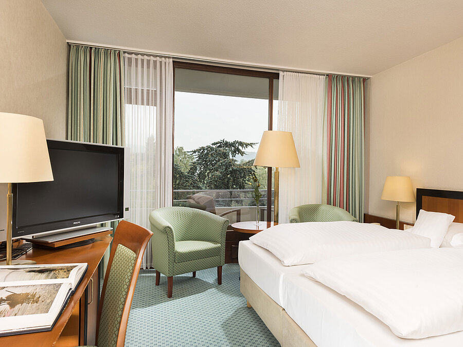 Habitación luminosa en el Maritim Hotel Bad Salzuflen con cama doble, zona de estar y acceso al balcón
