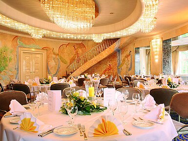 Sala de banquetes elegante con murales, lámparas y mesas decoradas