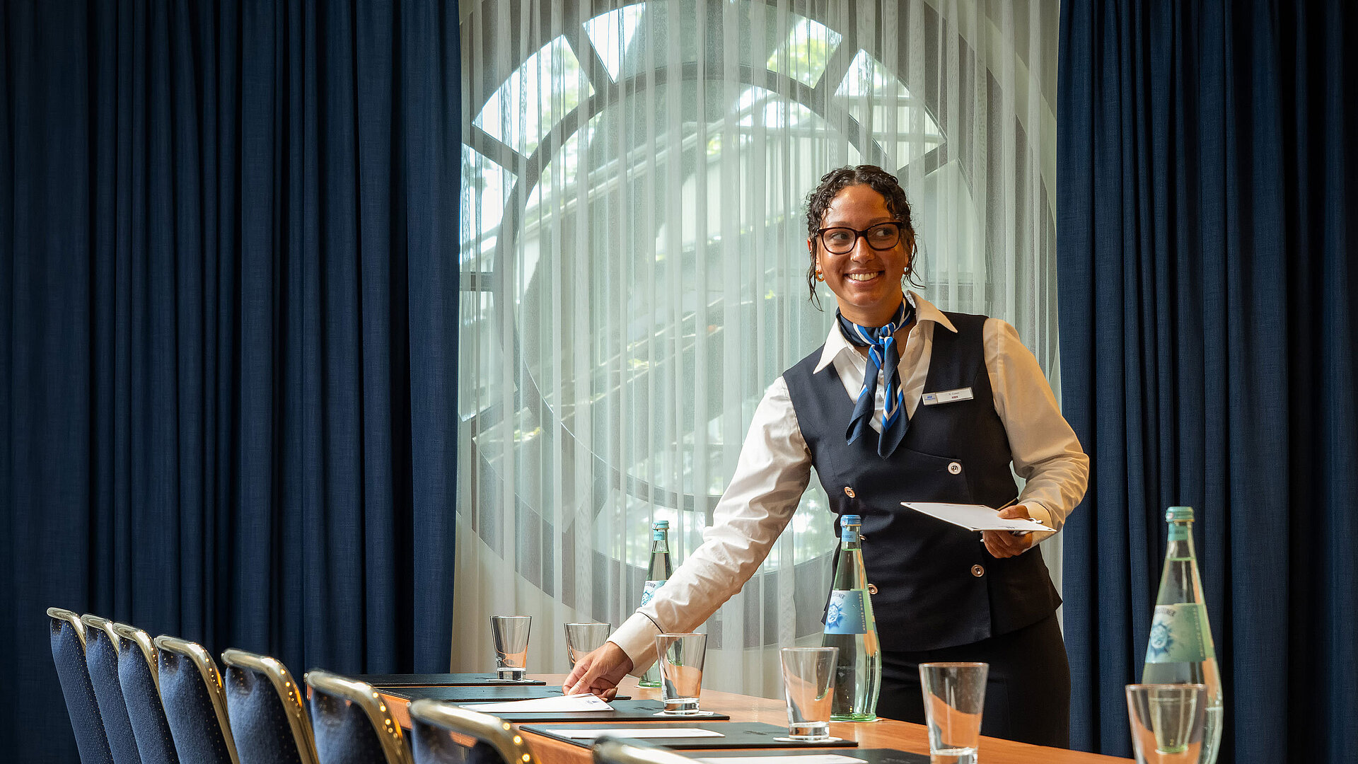 Dipendente del Maritim Hotel Köln prepara la sala conferenze con bevande e documenti