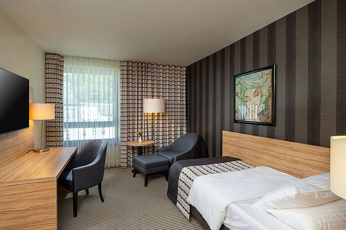 Habitación individual Classic Habitación Individual Classic del Maritim Hotel Königswinter con cama individual, zona de estar y gran ventana.