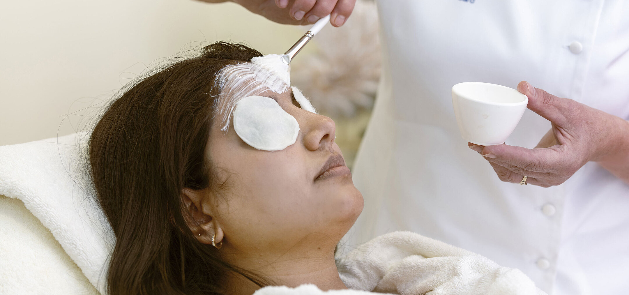 Soin du visage au Spa de l'hôtel Maritim : une femme reçoit un masque et des soins relaxants avec des cotons.
