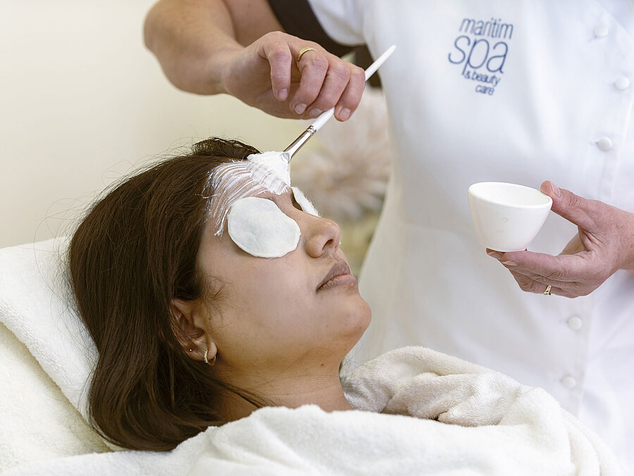 Soin du visage au Spa de l'hôtel Maritim : une femme reçoit un masque et des soins relaxants avec des cotons.