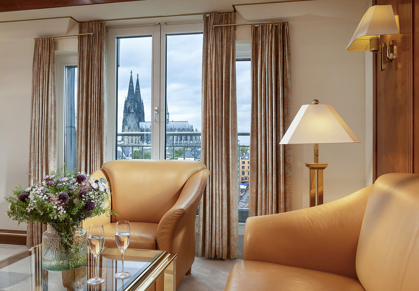 Elegante Suite Heumarkt al Maritim Hotel Colonia con comode poltrone in pelle e vista diretta sulla cattedrale di Colonia.
