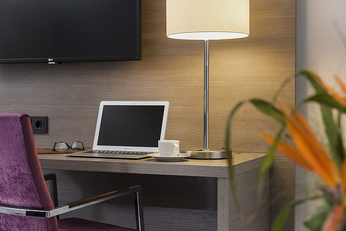 Bureau de l'hôtel Maritim Königswinter avec ordinateur portable, lunettes et lampe élégante.