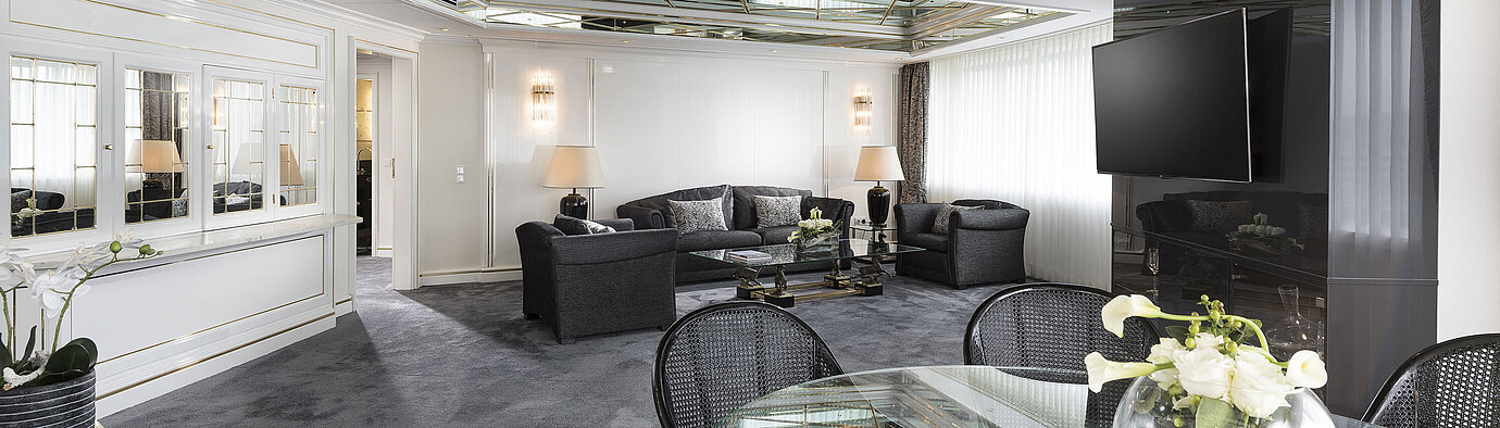 Luxury suite  Stylish living room of the luxury suite at Maritim Hotel Bonn with mirrored ceiling, modern furniture, and large dining table.