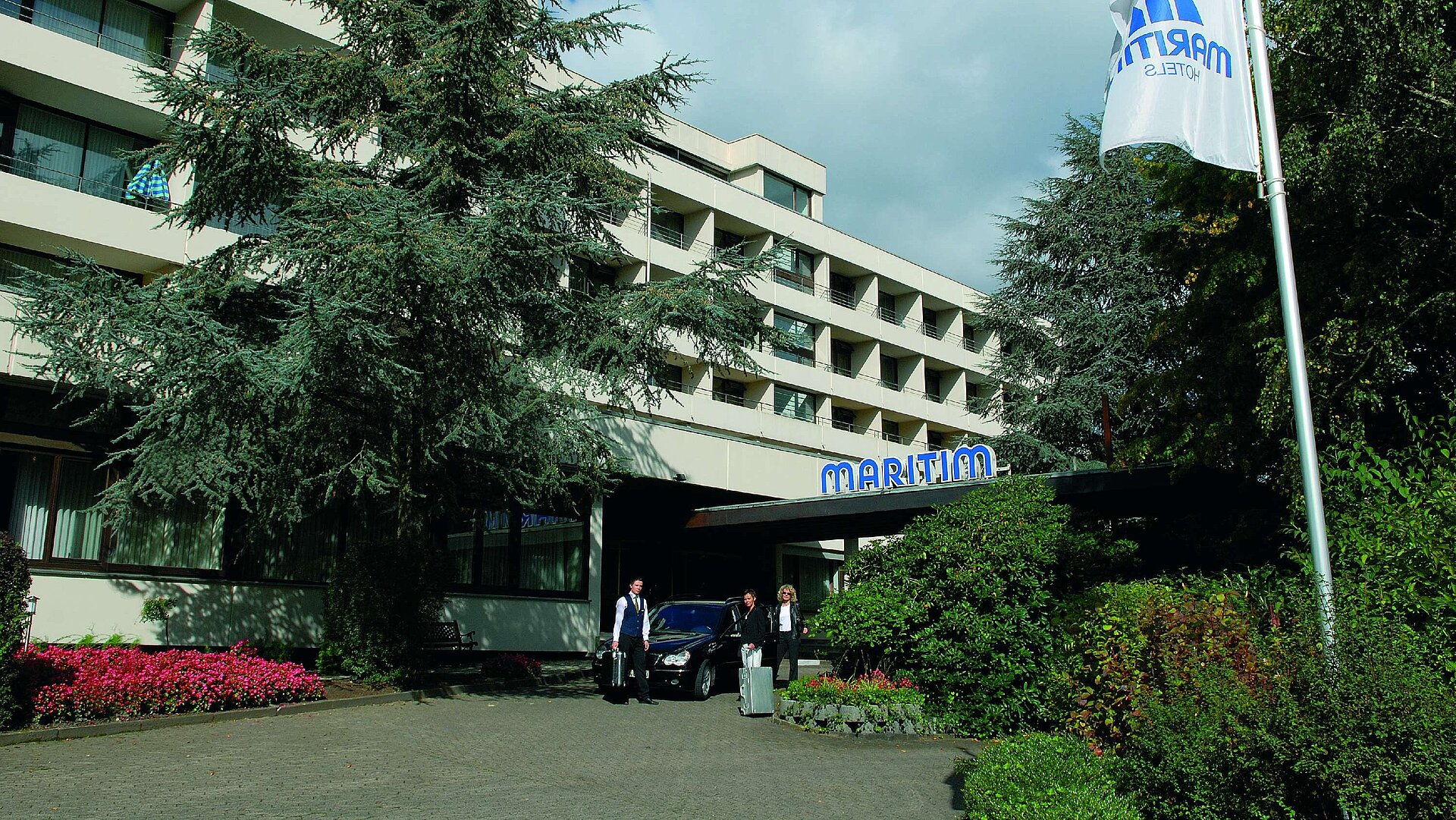 Entrée de l'hôtel Clients arrivant à l’hôtel Maritim Bad Salzuflen entouré de verdure et d’arbres