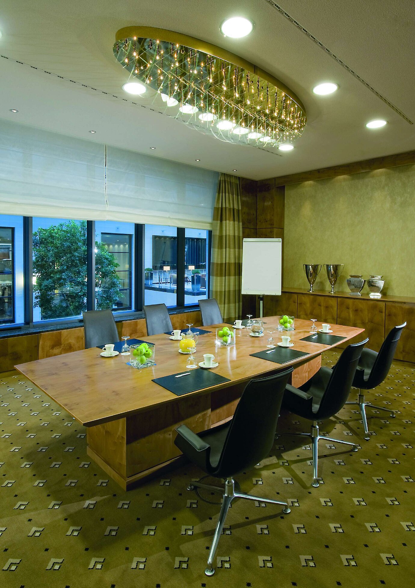 Modern meeting room at Maritim Hotel Düsseldorf with elegant wooden table, comfortable chairs, and stylish lighting.