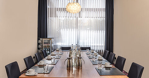 Petite salle de réunion avec baie vitrée, lumière du jour et boissons à l’hôtel Maritim Travemünde