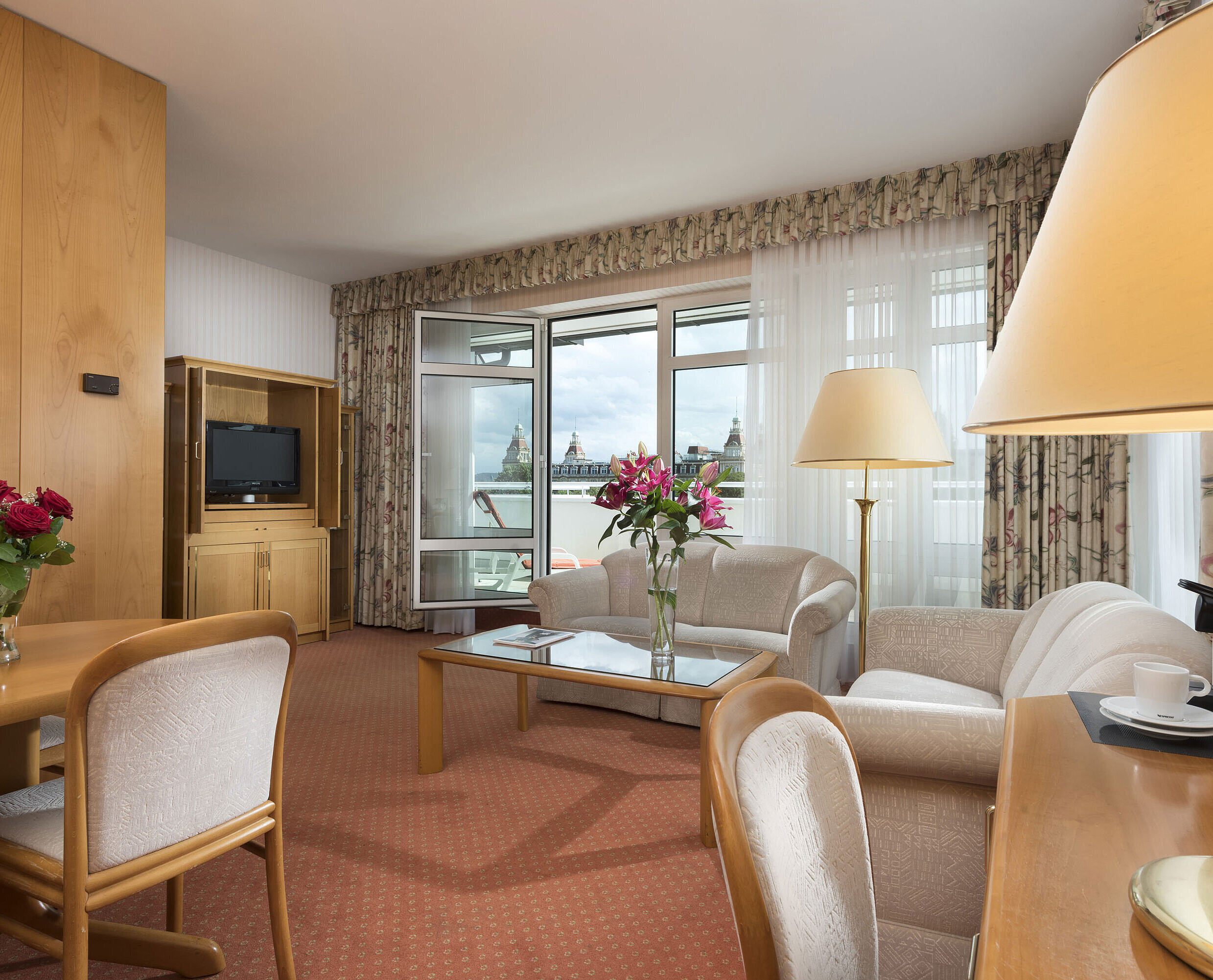 Junior suite Spacious living area with flowers, sofa, dining table and view at Maritim Hotel Bad Wildungen