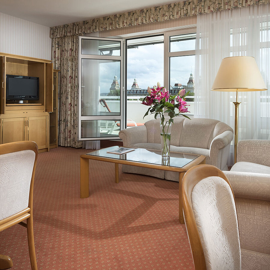 Spacious living area with flowers, sofa, dining table and view at Maritim Hotel Bad Wildungen