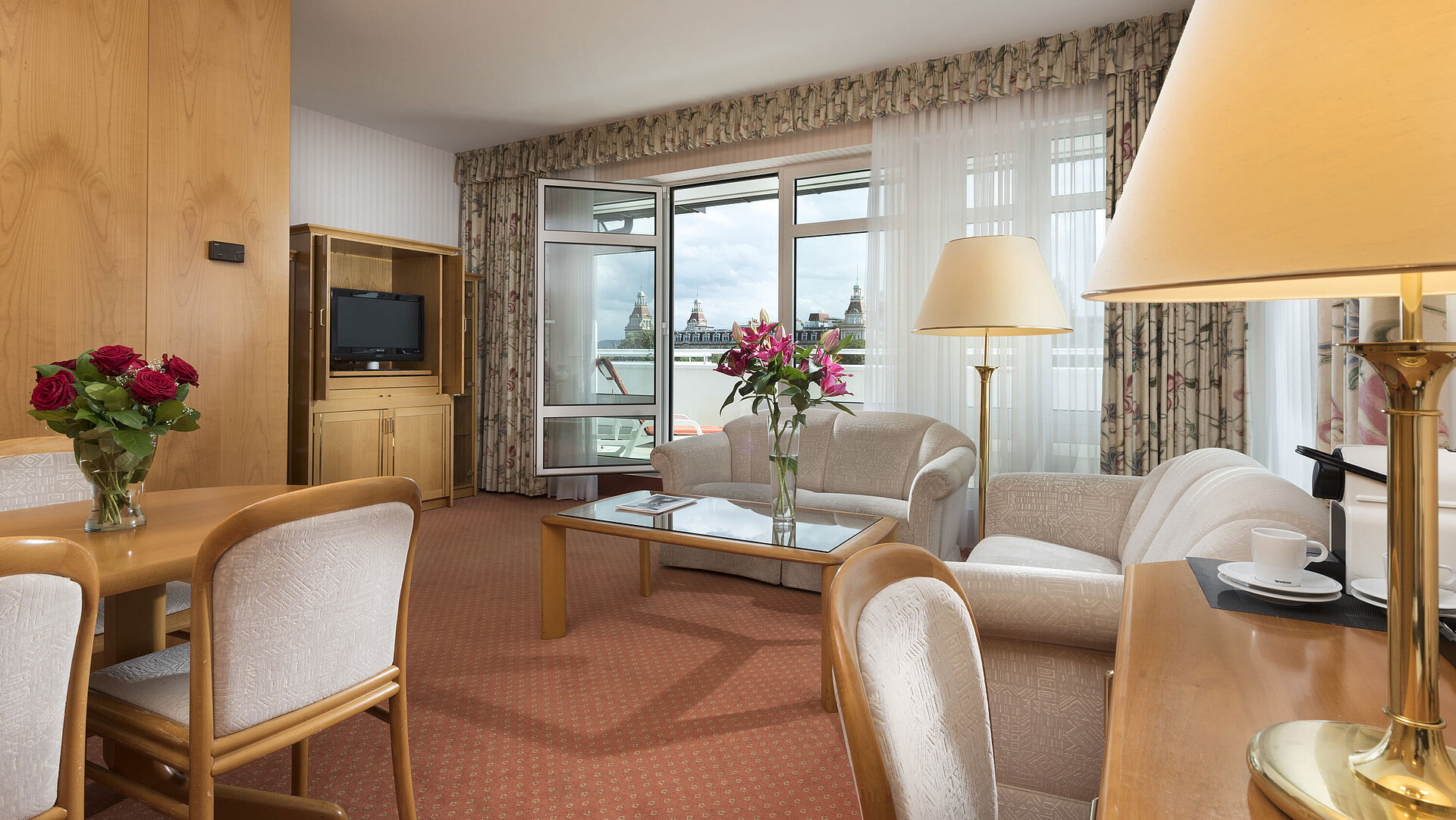 Spacious living area with flowers, sofa, dining table and view at Maritim Hotel Bad Wildungen