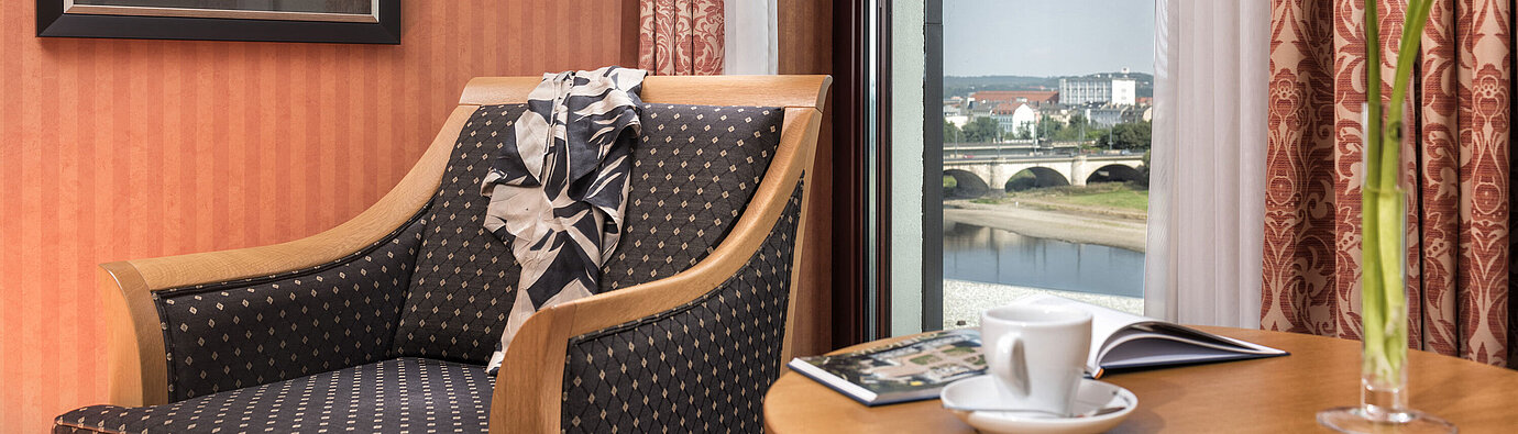 Detalle de un sillón acogedor en el Maritim Dresden con vista al río Elba y el puente,decorado con una bufanda en el respaldoDetalle de un sillón acogedor en el Maritim Dresden con vista al río Elba y el puente,decorado con una bufanda en el respaldo