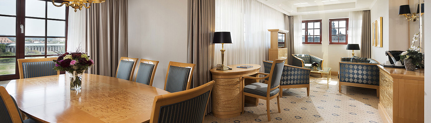 Suite Executive spaziosa al Maritim Hotel Dresden con elegante tavolo da pranzo, area salotto confortevole e vista sulla citt