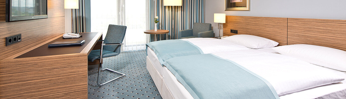Comfort room at Maritim Hotel Darmstadt with modern design, desk, cozy seating area, and large windows.