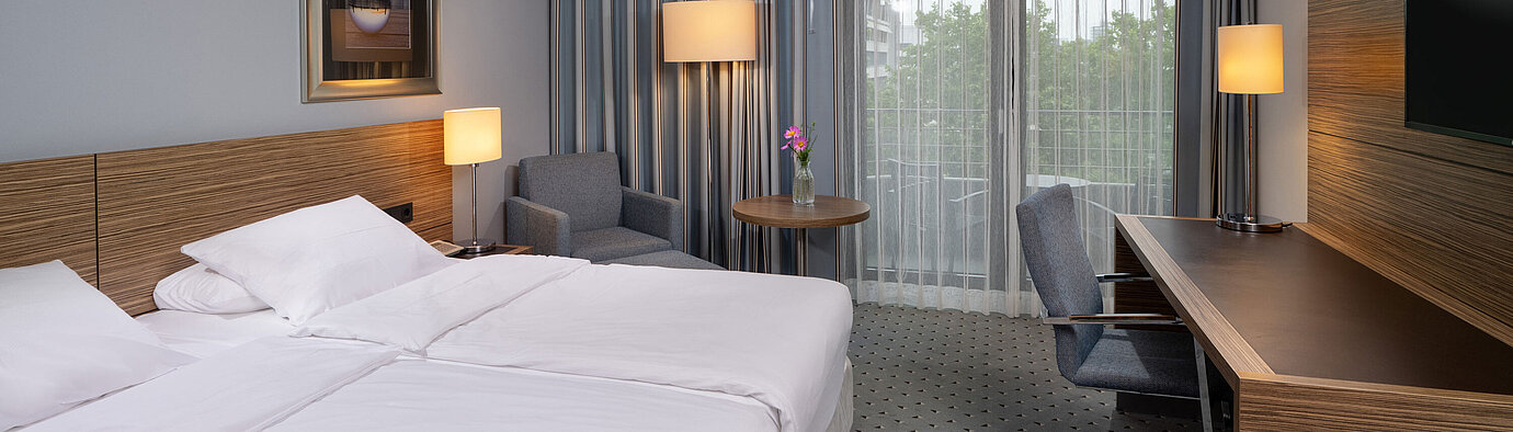 Vista completa della camera Comfort al Maritim Hotel Darmstadt con letto, scrivania e accesso al balcone
