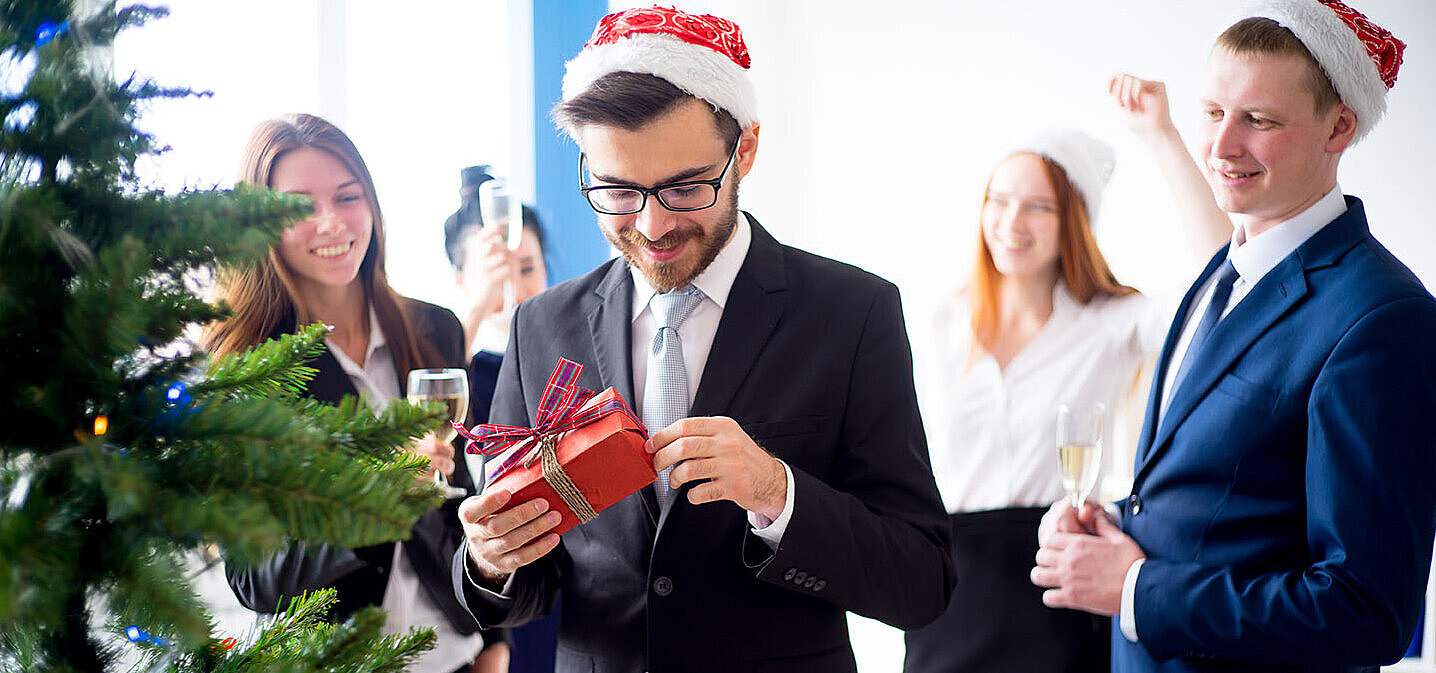 © Nichizhenova Elena - AdobeStock.com Colleagues exchanging gifts at a hotel Christmas party