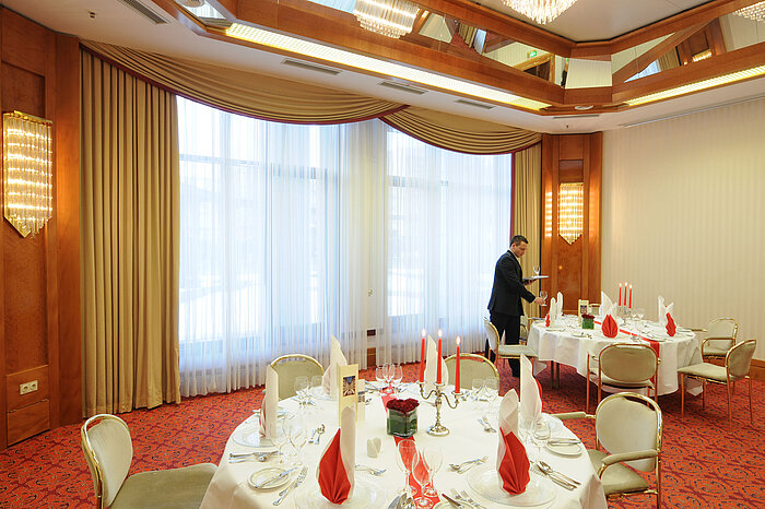Salón de banquetes elegantemente preparado con velas y servilletas rojas en el Maritim Hotel Magdeburg.